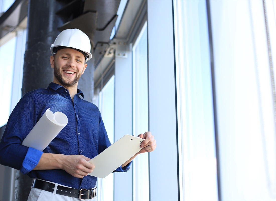Insurance by Industry - Shot of Smiling Male Architect Wearing Hardhat and Inspecting New Building