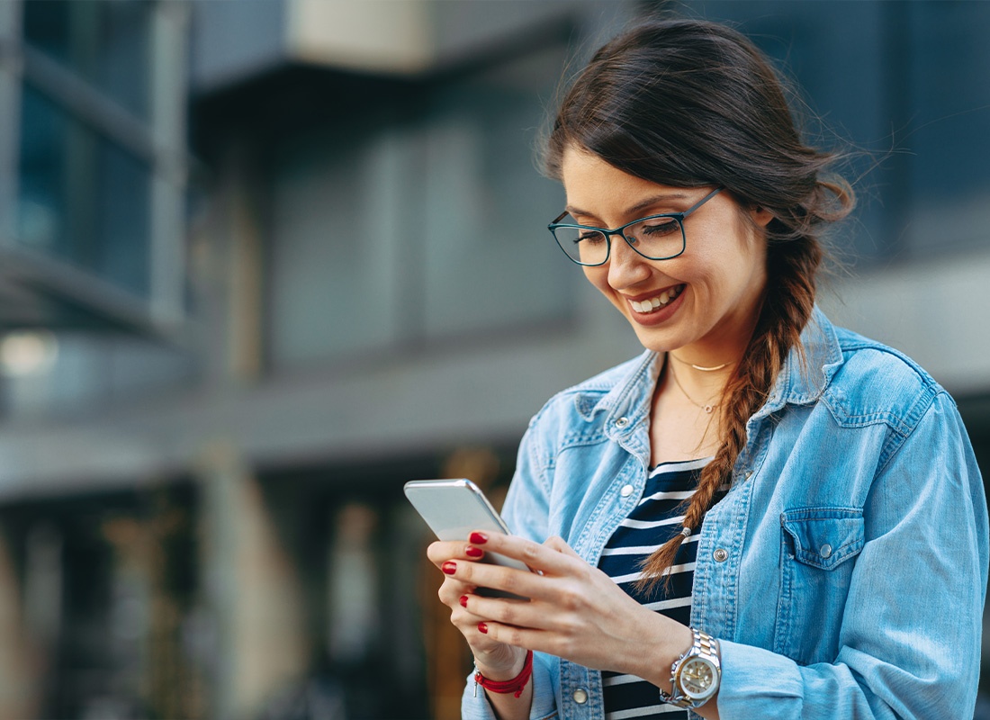 Read Our Reviews - Young Woman Reading a Message on the Phone in the City